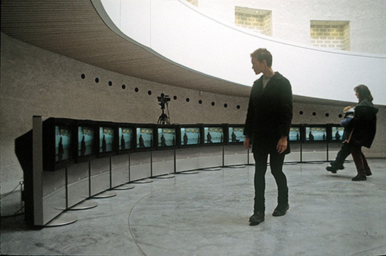 Installation — Installationview (2), Christian Skeel in collaboration w. Morten Skriver Split Second 1997 installation Collection: Esbjerg Art Museum Split Second is a video-installation, which consists of 13 monitors and a camera. The placing of the monitors forms a curve. In order to record the visitors the camera is situated in the middle of that curve just behind the monitors. The recordings are distributed among the screens so that image 1 becomes a still on screen 1; image 2 becomes a still on screen 2 etc. This gives you the opportunity to study your movements as if animated in a cartoon, but only for an instant because the stills are left standing for no ore than 1 or 2 seconds. You see yourself in a kind of delayed present. Split Second is made in collaboration with B&O and Anders Lehmann. Split Second is from 1997 and has been exhibited at Esbjerg Art Museum, Arken - Museum of Contemporary Art, Trapholt Art Museum and Kulturhuset in Stockholm (Sweden).