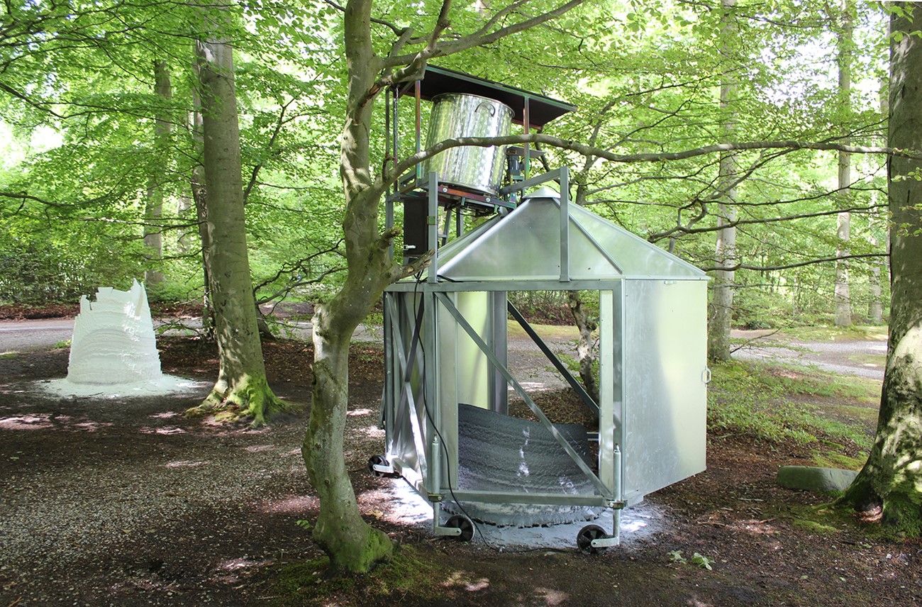 Skovinstrument, 2017, Wax, iron, heat element, motor, aluminium and electronics, 280 x 240 x 240 cm, The machine produces cone shaped objects of wax. The machine melts the wax which drips down on a rotating iron plate. From here the drops are flung in a circle on the ground where they harden. Exhibited at ARoS, Ballehage beach, Aarhus 2017.