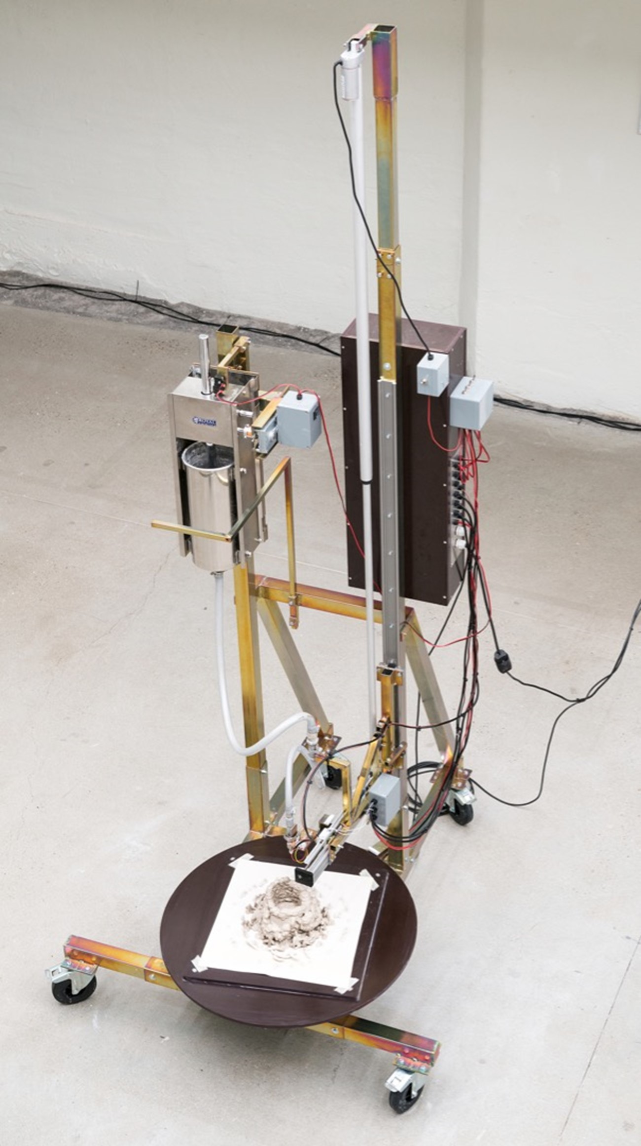 Henrik Menné: L5, 2021, iron, wood, motor, sausage press, compressed air hoses, electronics and clay, 260h x 160w x 10d cm (installation view).